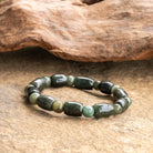 Jade bracelet with oval beads on natural stone surface.