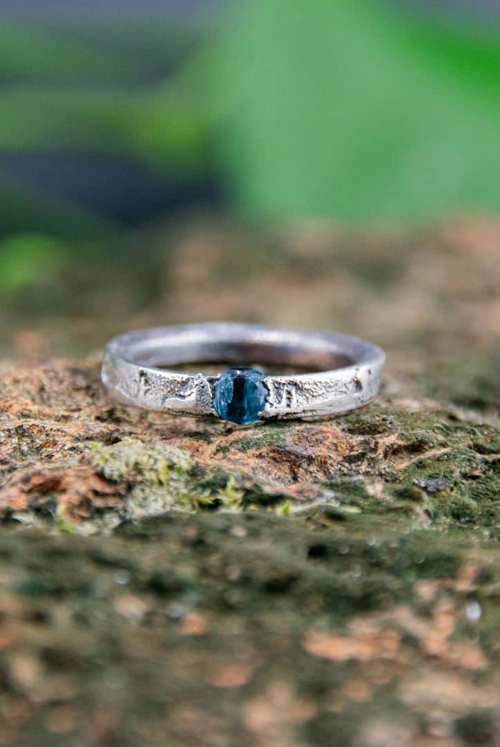 Blue Sky zirconia sand casting ring showcasing unique texture and design on a natural stone background.