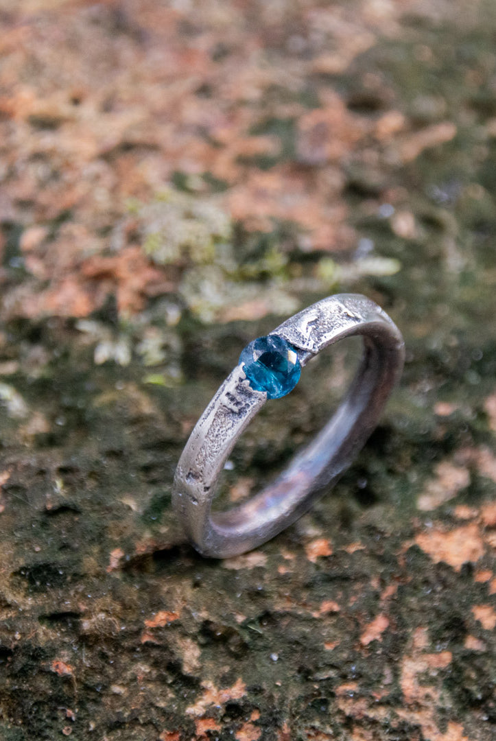 Unique Blue Sky Zirconia Sand Casting Ring with organic texture and blue stone on natural background.