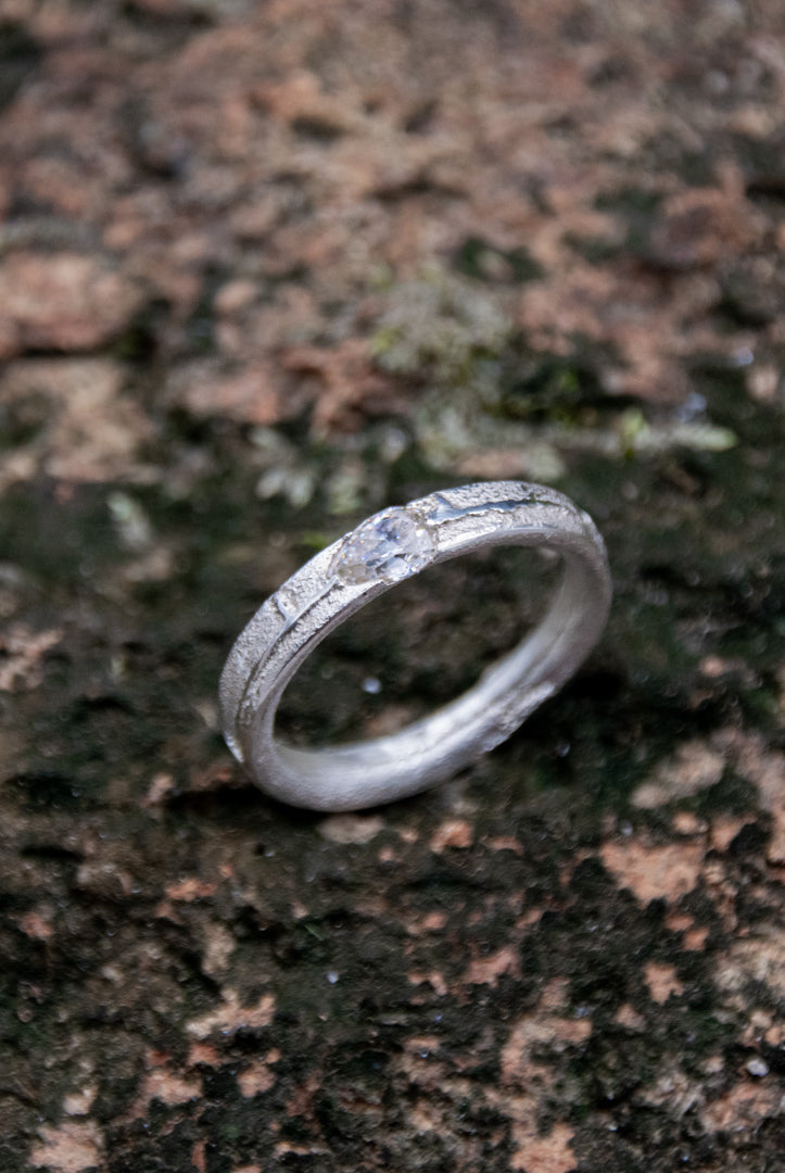 Unique crystal zirconia sand casting ring on textured stone background, showcasing artisanal craftsmanship and organic design.