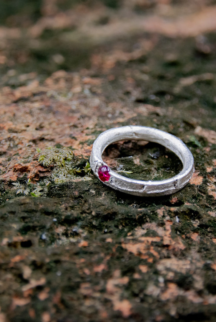 Round Ruby Sand Casting Ring with organic texture, showcasing artisanal craftsmanship on a natural stone background.