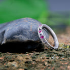 Three Little Ruby Sand Casting Ring showcasing unique textures and rubies set on a rock surface.