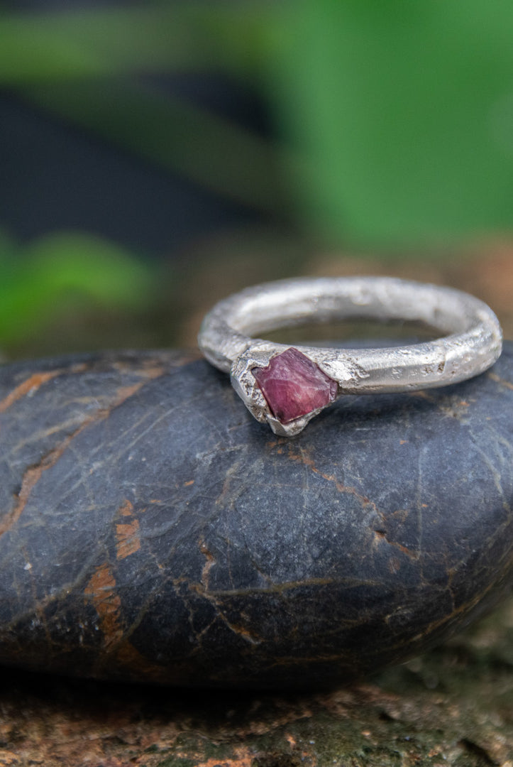 Raw ruby round ring on a stone, showcasing unique sand casting craftsmanship and organic textures.