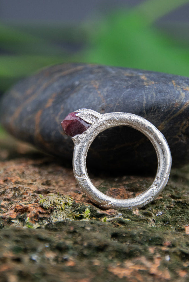 Raw ruby round ring featured on textured stone, showcasing unique sand casting finish and artisanal design.
