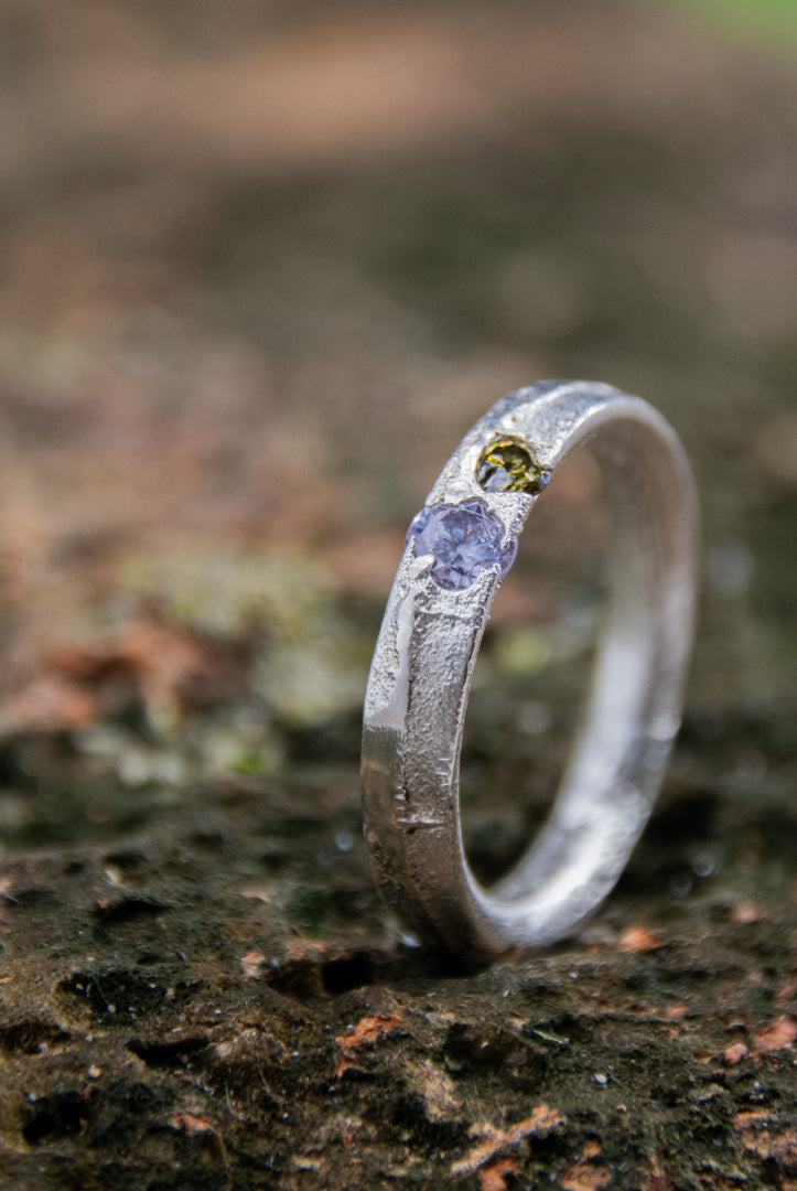 Close-up of a unique purple and brownish zirconia sand casting ring on textured surface.