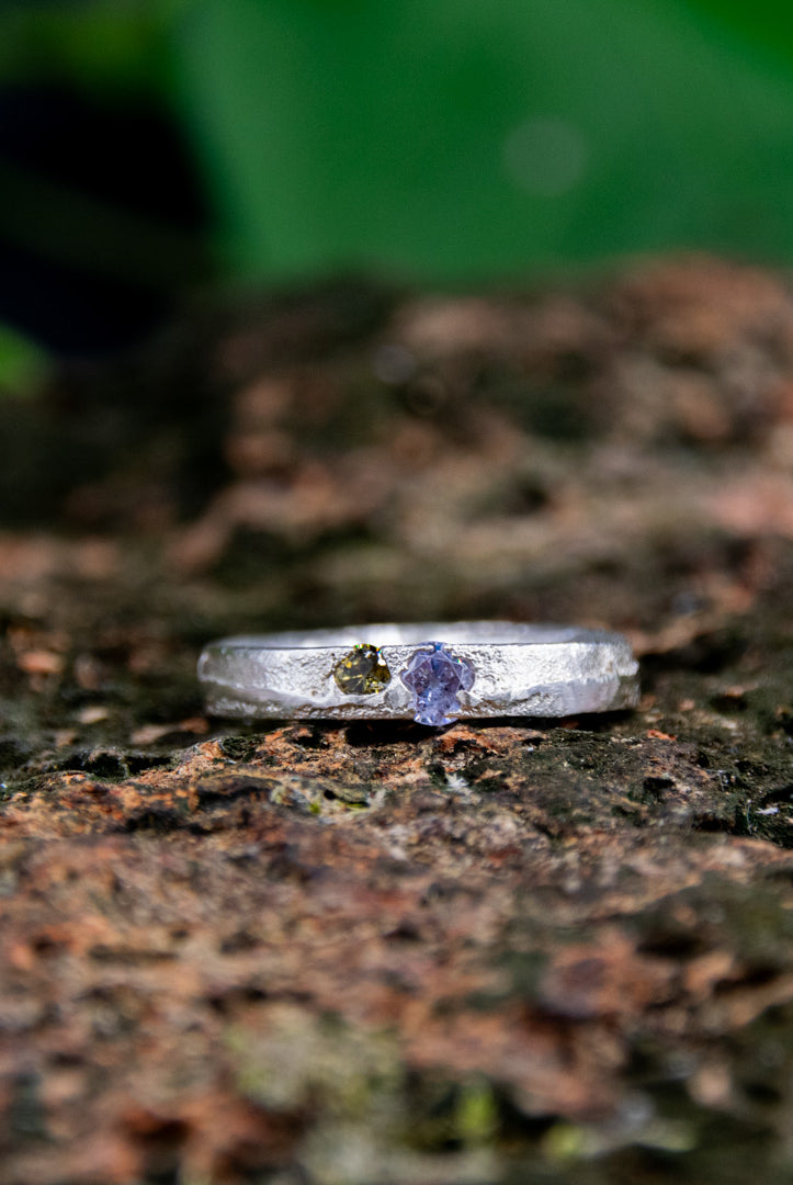 Purple and brownish zirconia sand casting ring on textured surface, showcasing unique artisan craftsmanship.