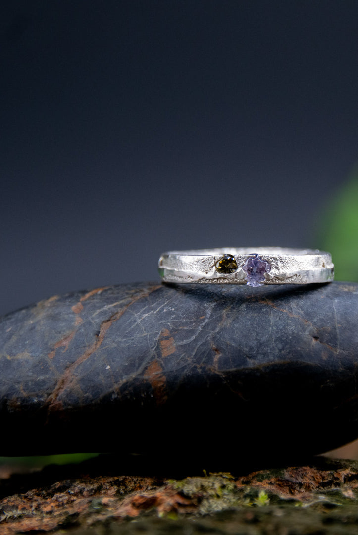 Purple and brownish zirconia sand casting ring displayed on a smooth stone, showcasing unique artisanal craftsmanship.