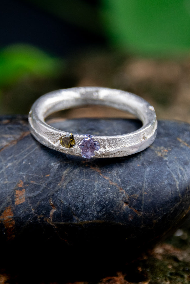Purple and brown zirconia sandcasting ring on dark stone, showcasing unique textures and artisanal craftsmanship.