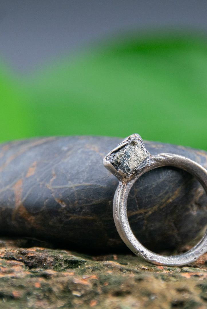 Unique pyrite gemstone sandcasting ring displayed on a textured stone surface, showcasing artisanal craftsmanship.