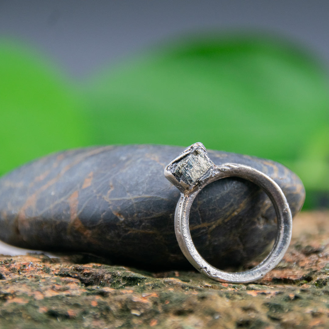 Unique pyrite gemstone sandcasting ring displayed on a textured stone surface, showcasing artisanal craftsmanship.