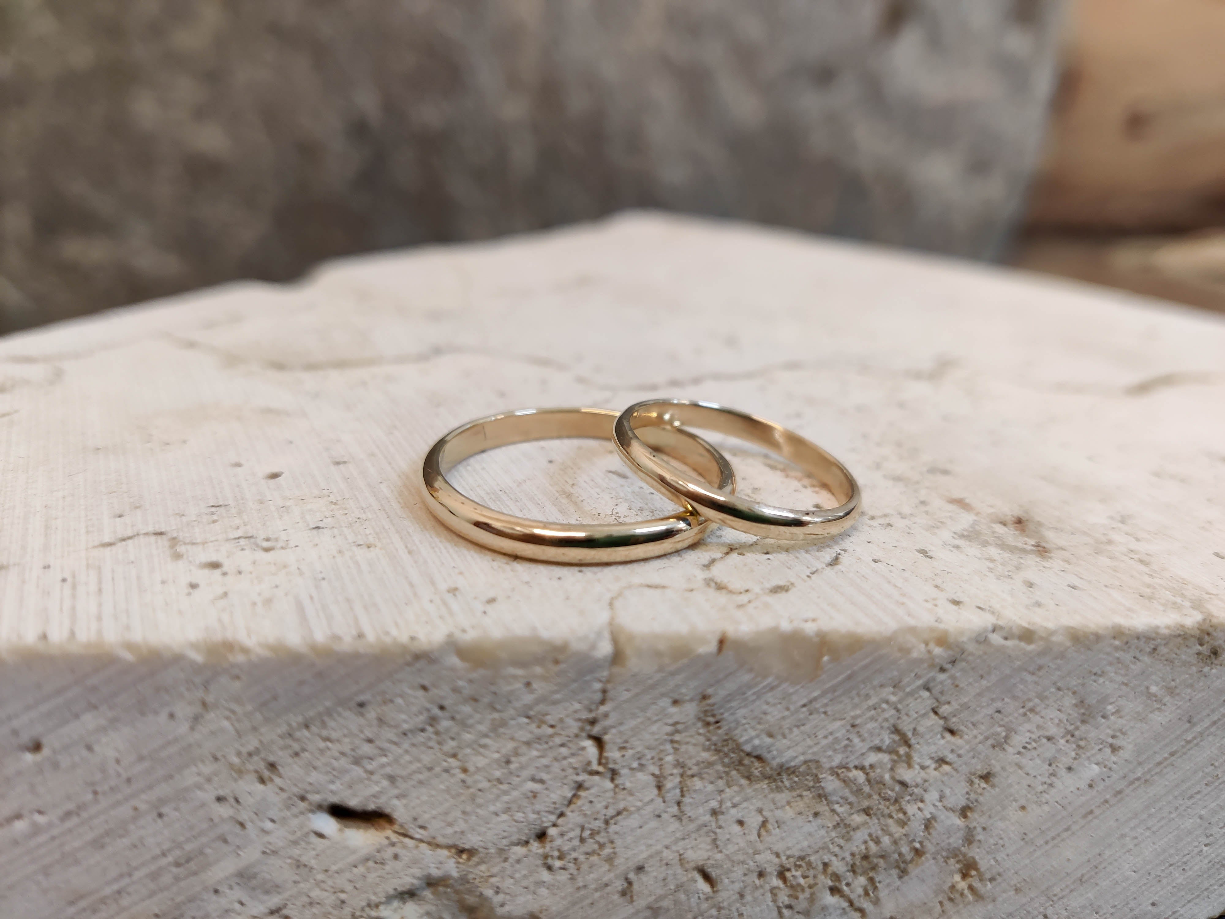 Finished gold wedding bands displayed on stone, crafted in Koh Chang jewelry studio.