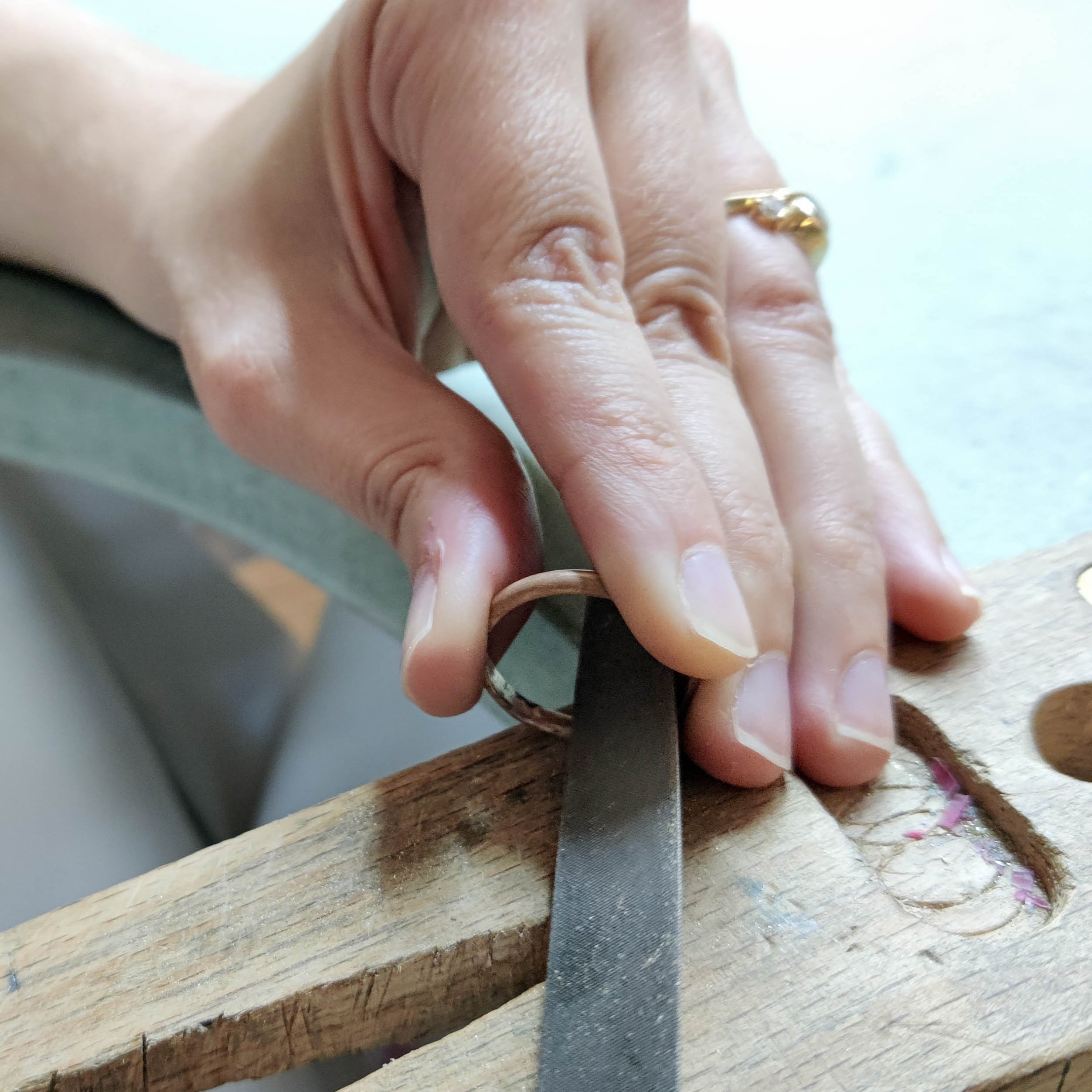 Filing and refining handmade gold rings during jewelry workshop in Koh Chang.