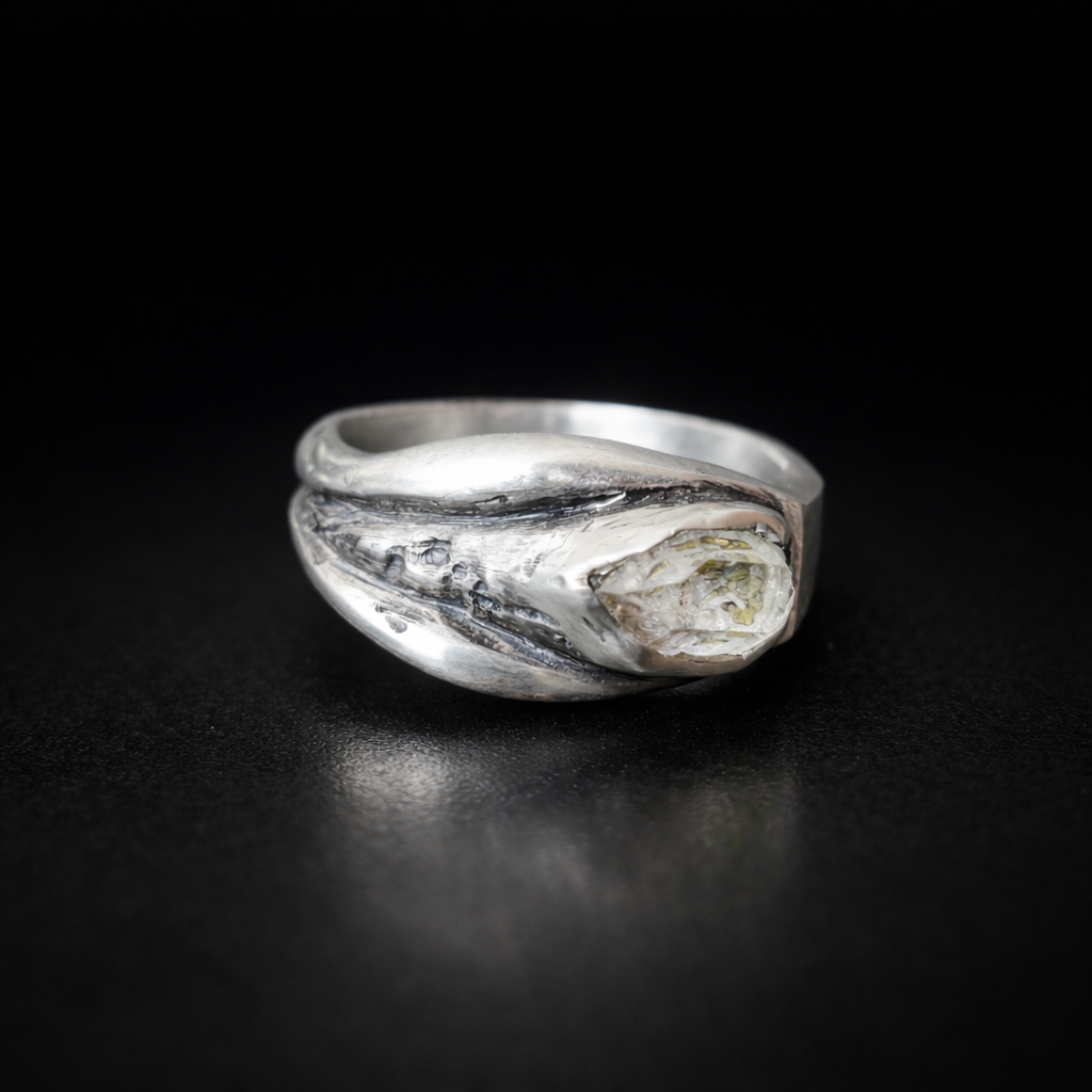 Silver ring with a textured design as a vulva on a black background