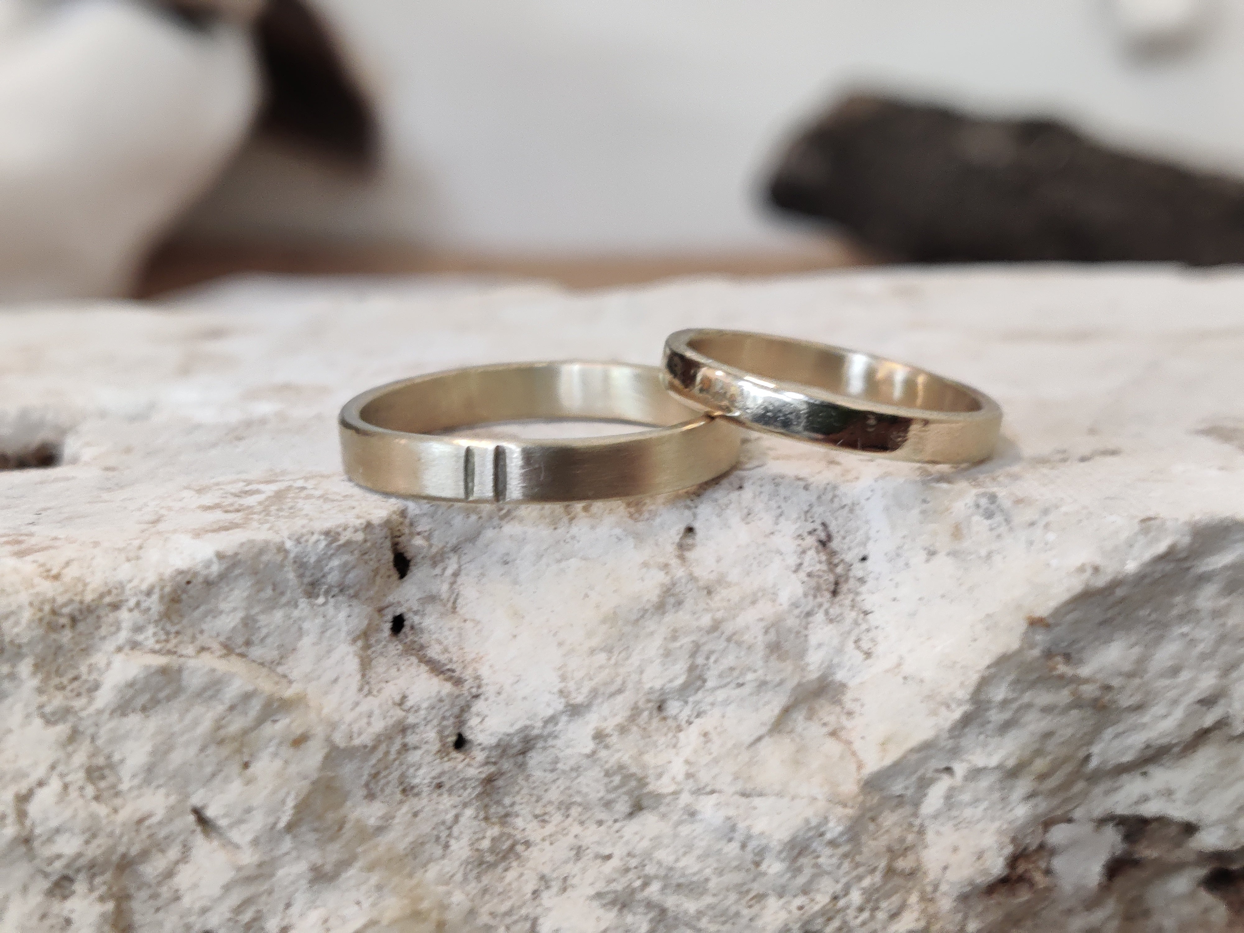 Custom handmade gold wedding rings placed on natural stone in Koh Chang jewelry studio.