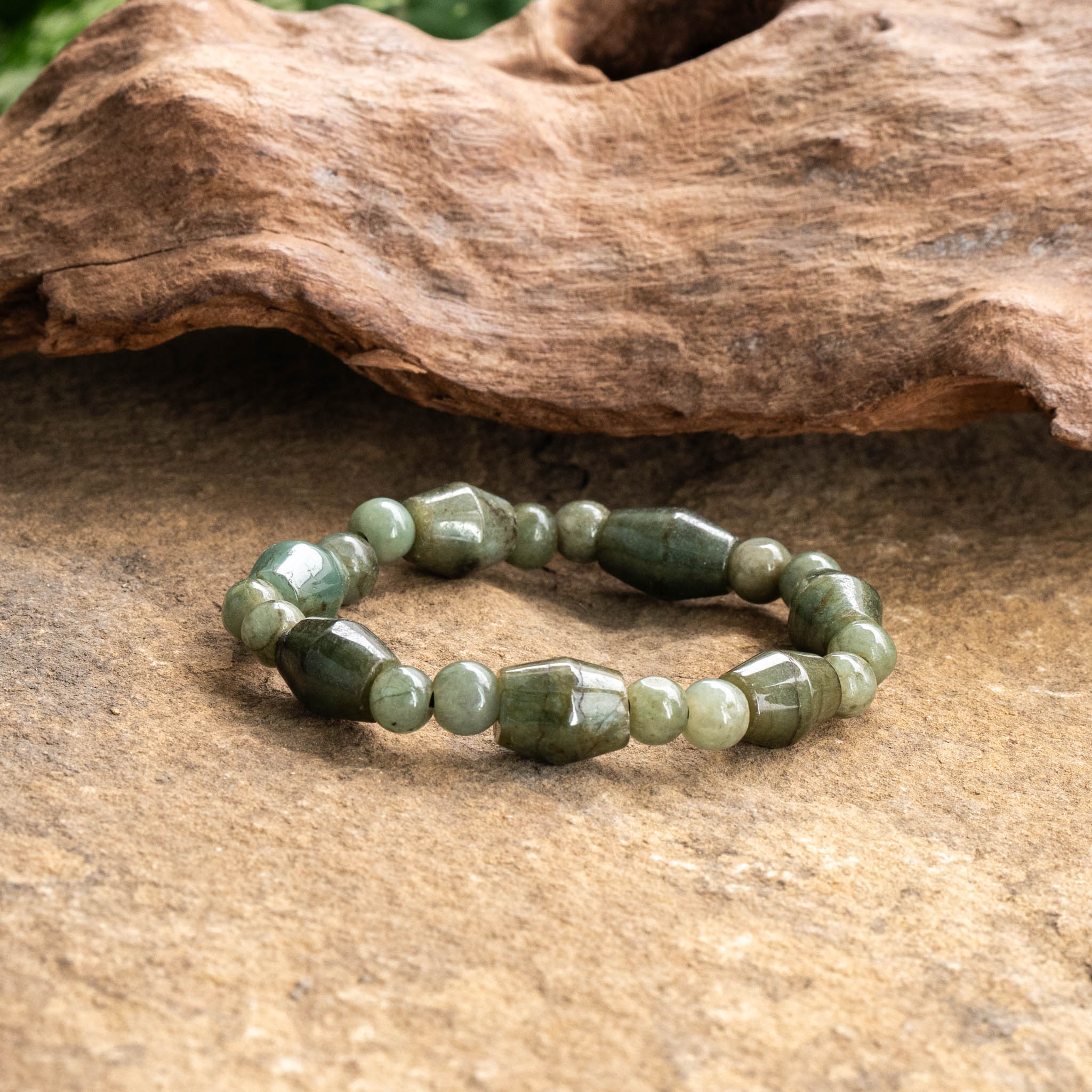 Unique Jade bracelet with handcrafted gemstone beads on a natural wood background.