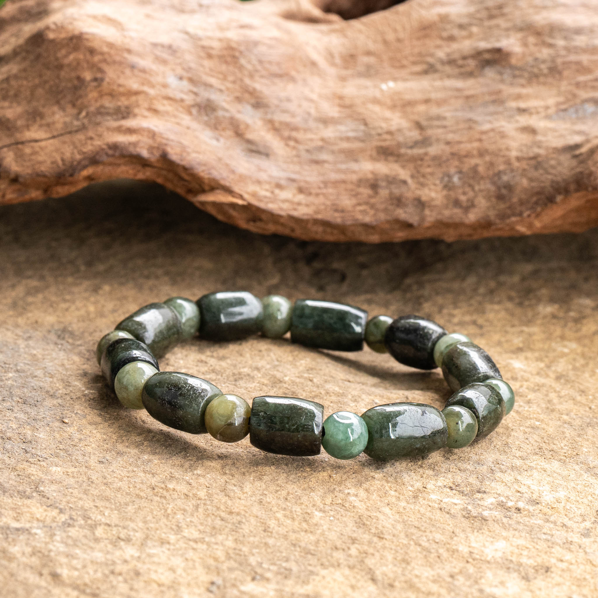 Jade bracelet with oval beads on natural stone surface.