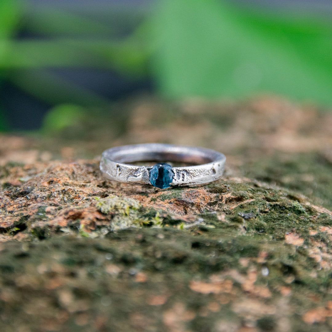 Blue Sky zirconia sand casting ring showcasing unique texture and design on a natural stone background.