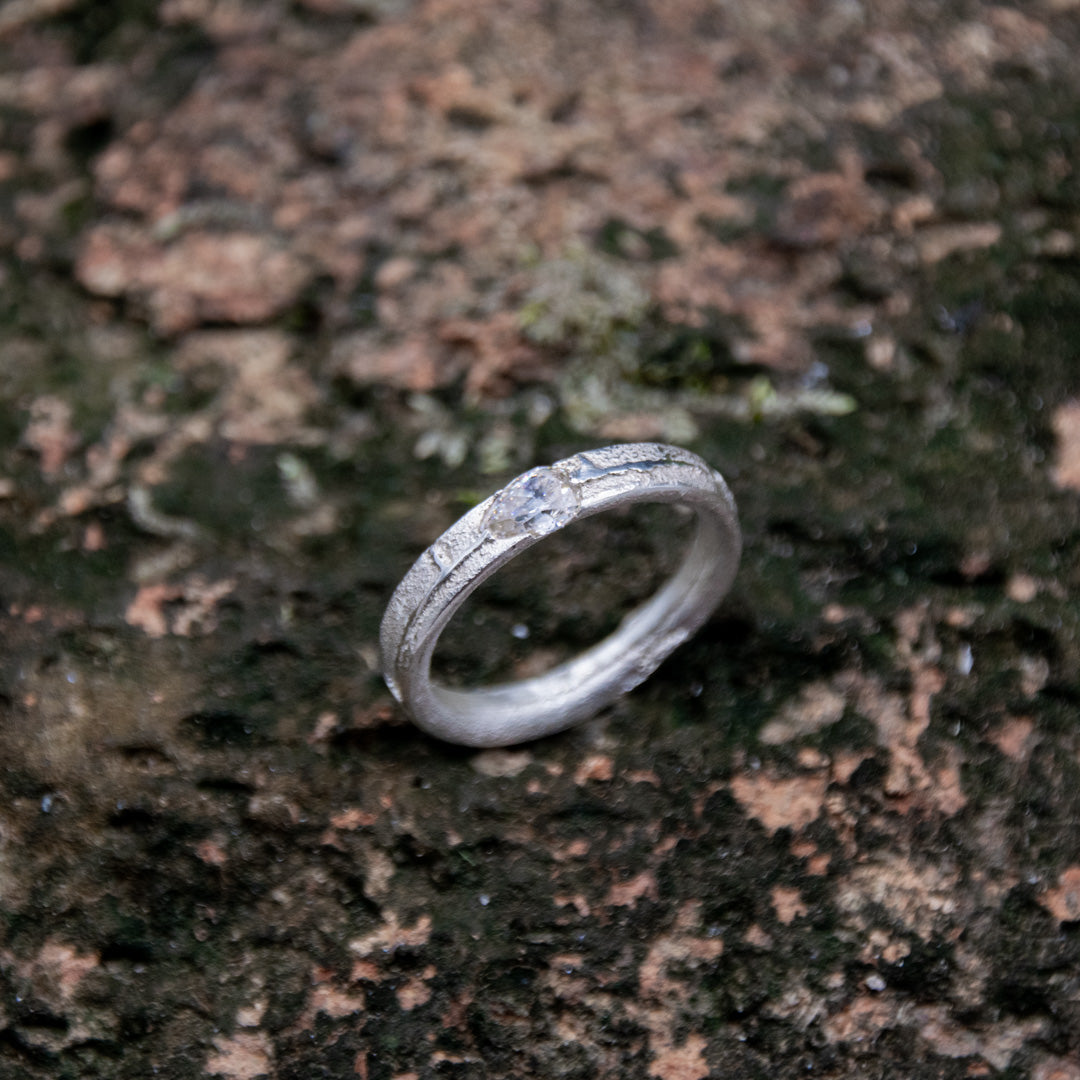 Unique crystal zirconia sand casting ring on textured stone background, showcasing artisanal craftsmanship and organic design.