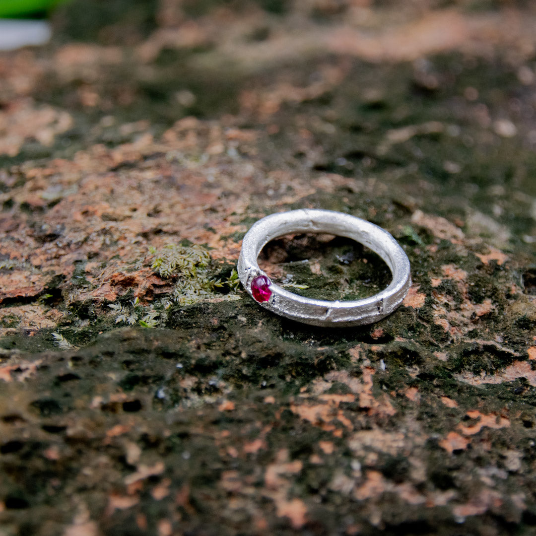 Round Ruby Sand Casting Ring with organic texture, showcasing artisanal craftsmanship on a natural stone background.