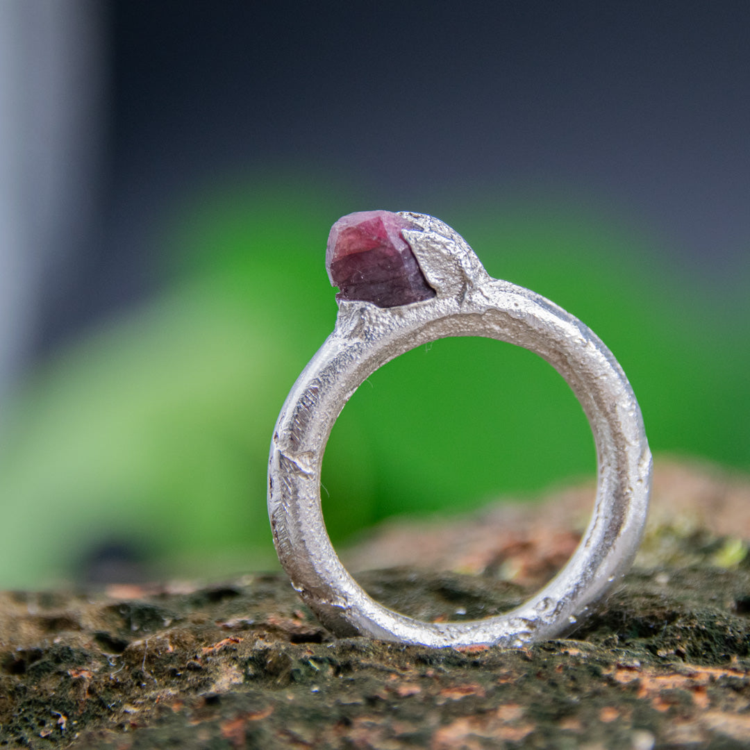Raw ruby round ring in sand cast silver, showcasing organic texture and one-of-a-kind design.