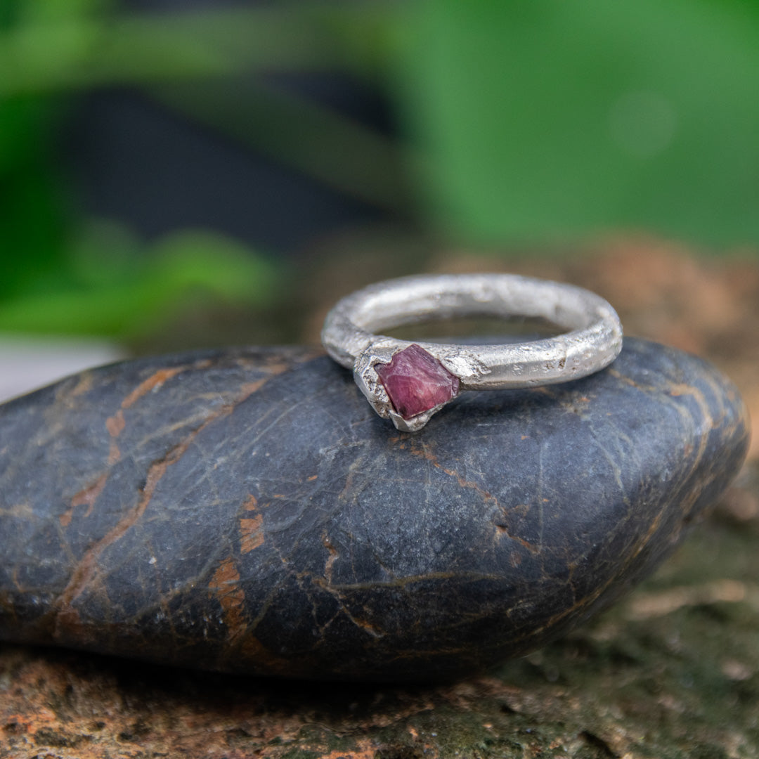 Raw ruby round ring on a stone, showcasing unique sand casting craftsmanship and organic textures.