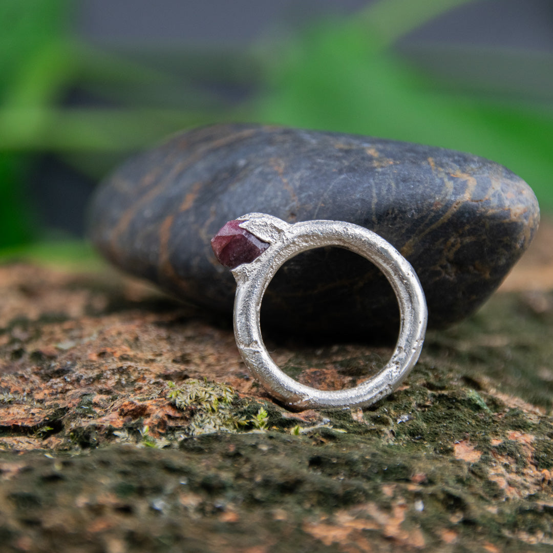 Raw ruby round ring featured on textured stone, showcasing unique sand casting finish and artisanal design.