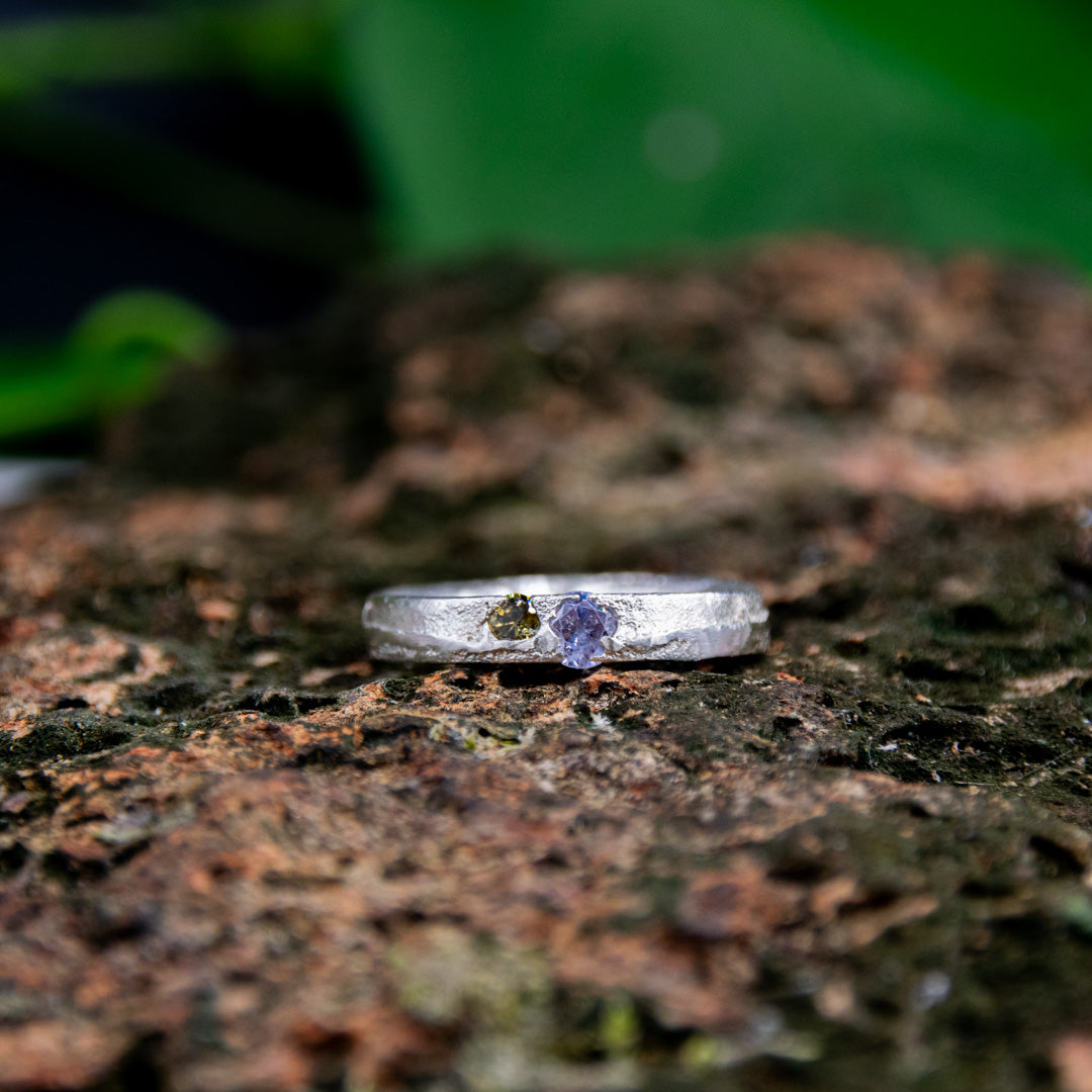 Purple and brownish zirconia sand casting ring on textured surface, showcasing unique artisan craftsmanship.