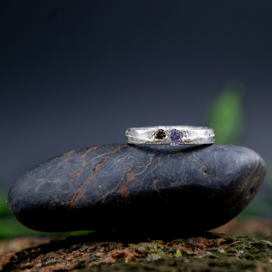 Purple and brownish zirconia sand casting ring displayed on a smooth stone, showcasing unique artisanal craftsmanship.